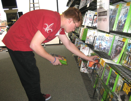Youth pulls DVD's off of a shelf at his job site